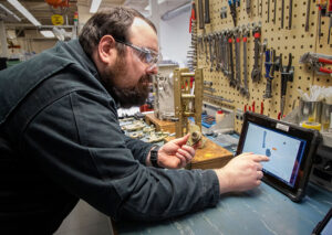 Man leans over work countertop while interacting with a tablet loaded with the BILT app