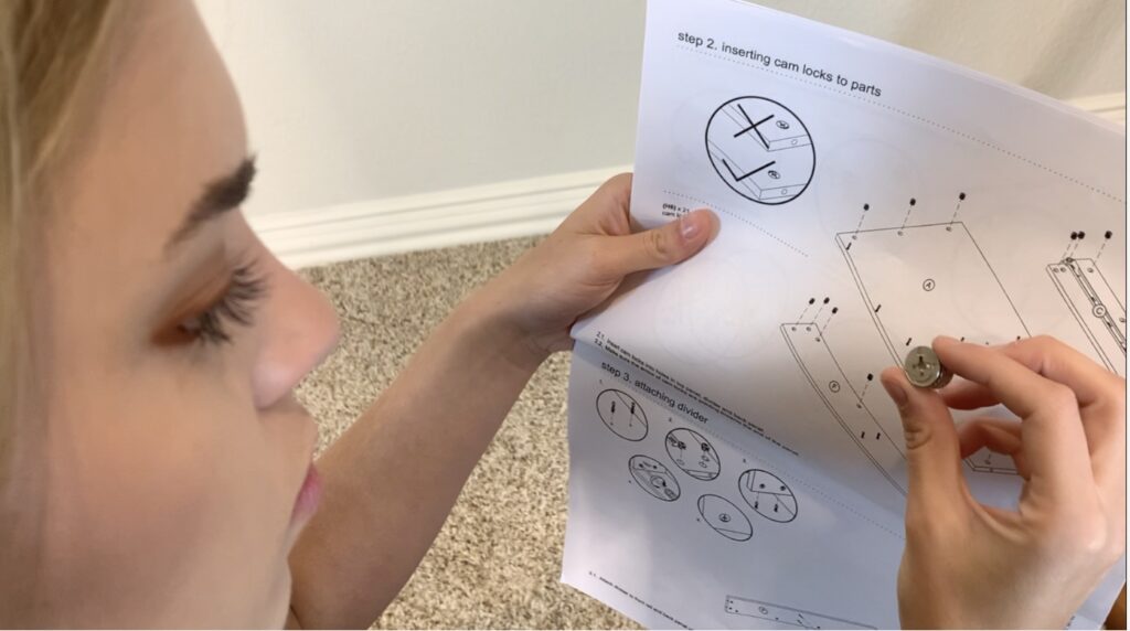Young woman in a home setting examines paper instructions while holding a small part in her right hand